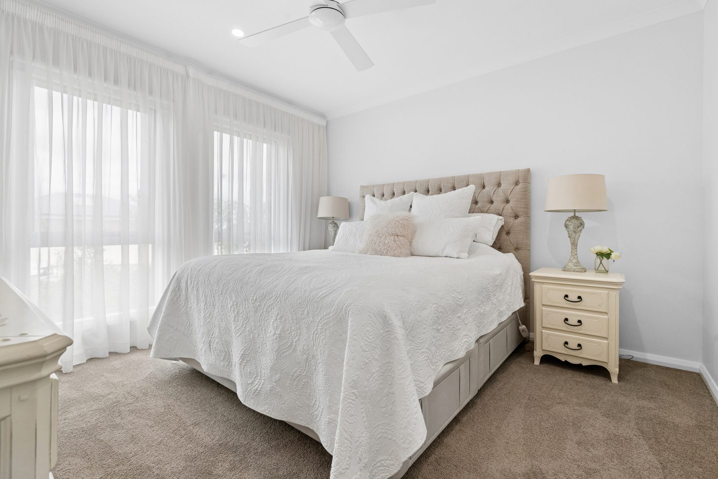 Main bedroom with broad windows, neutral finishes and a ceiling fan
