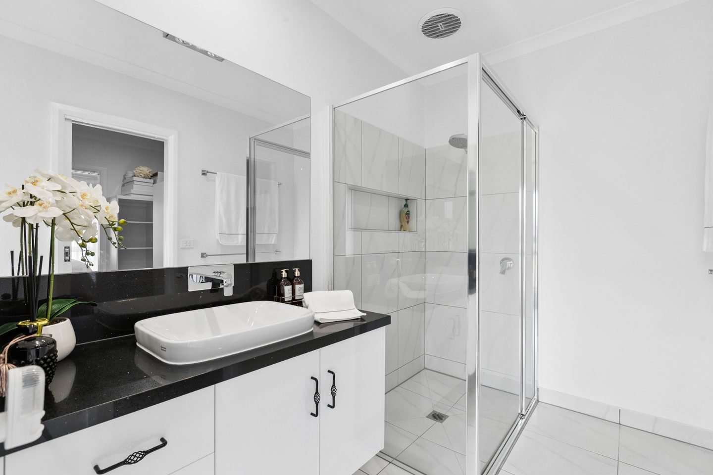 Ensuite with a glass shower, white vanity and dark benchtop